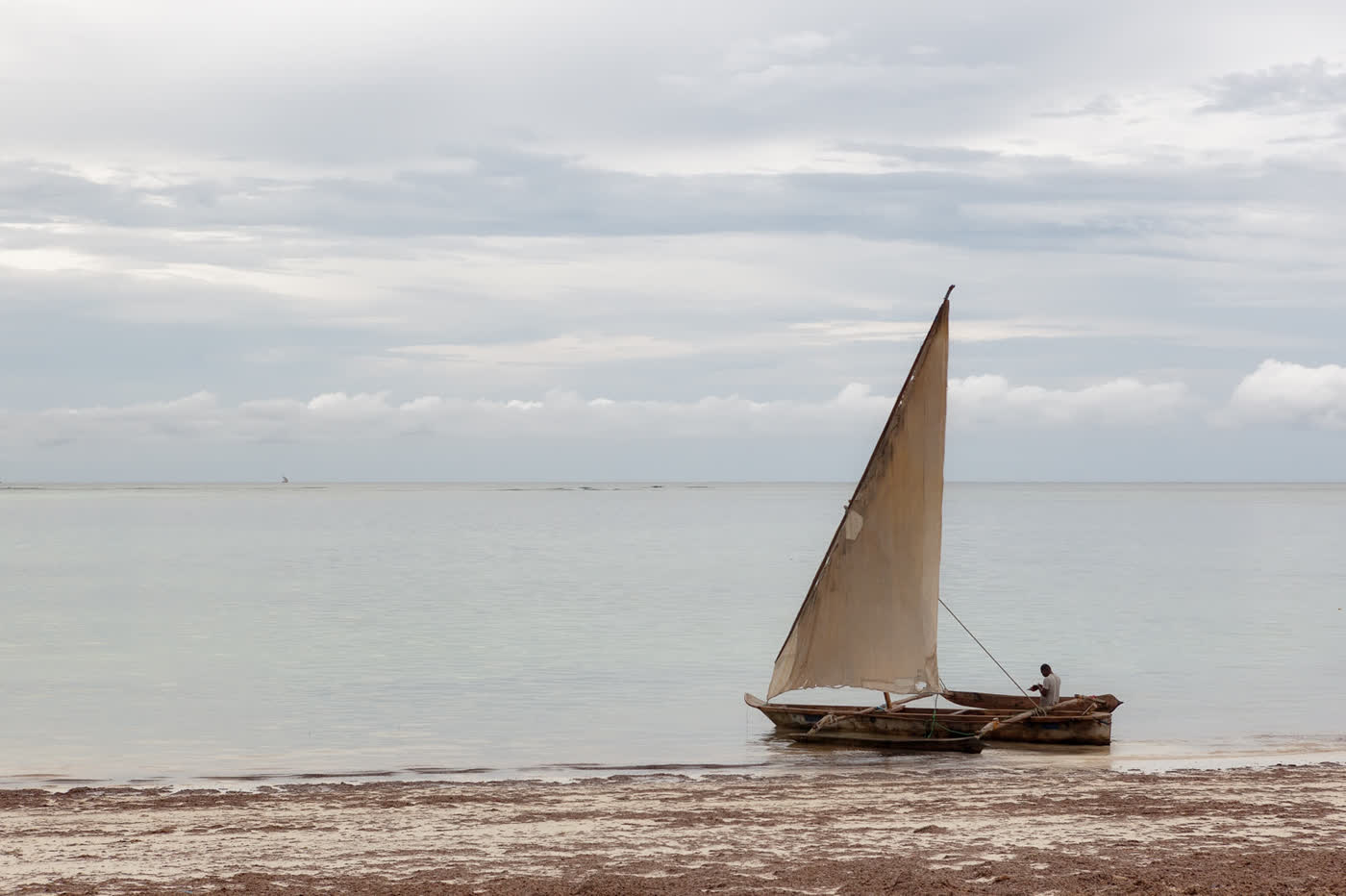 Traditional wooden dhow sailing boat on calm Zanzibar water